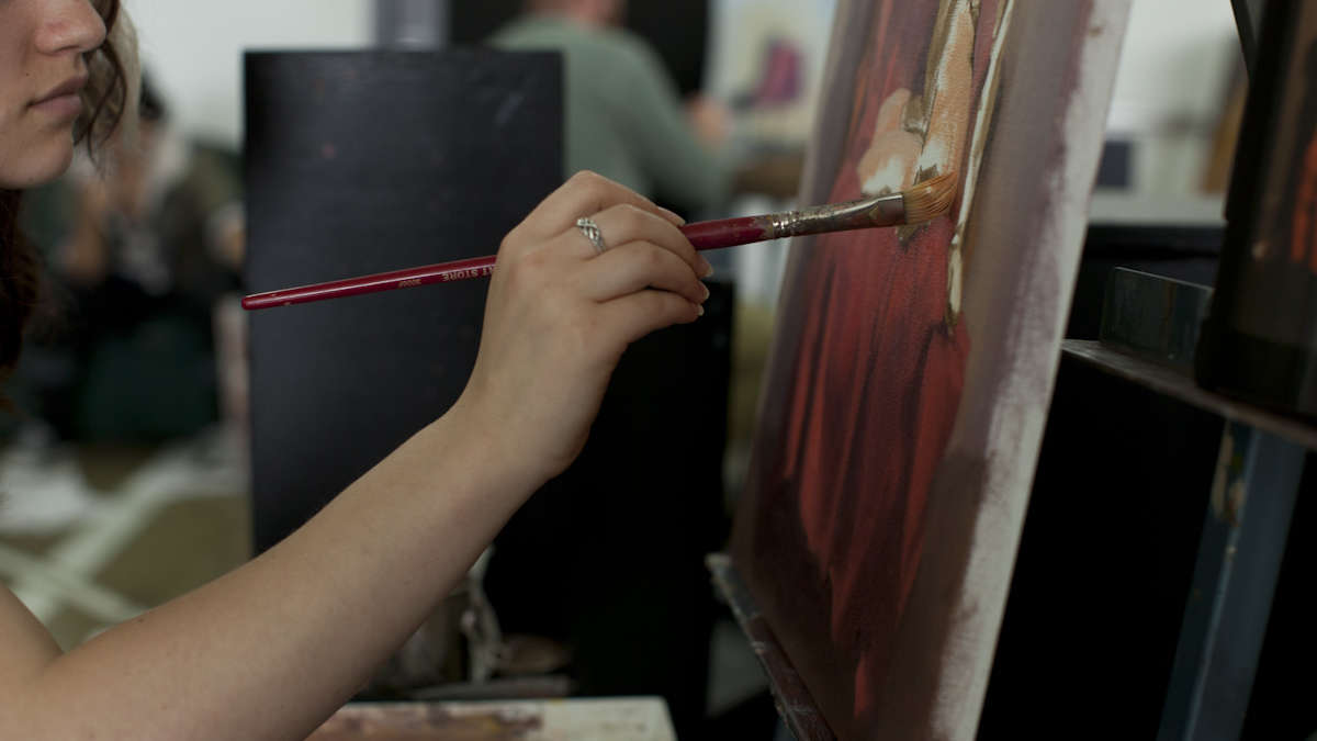 girl painting red on canvas