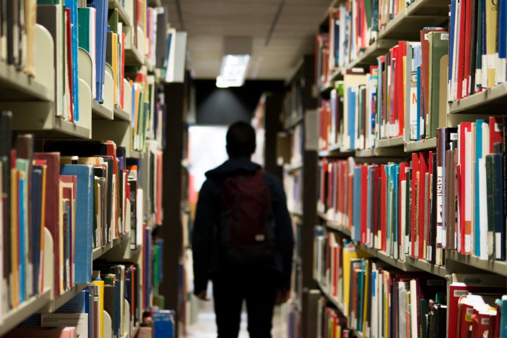 student in between library shelves