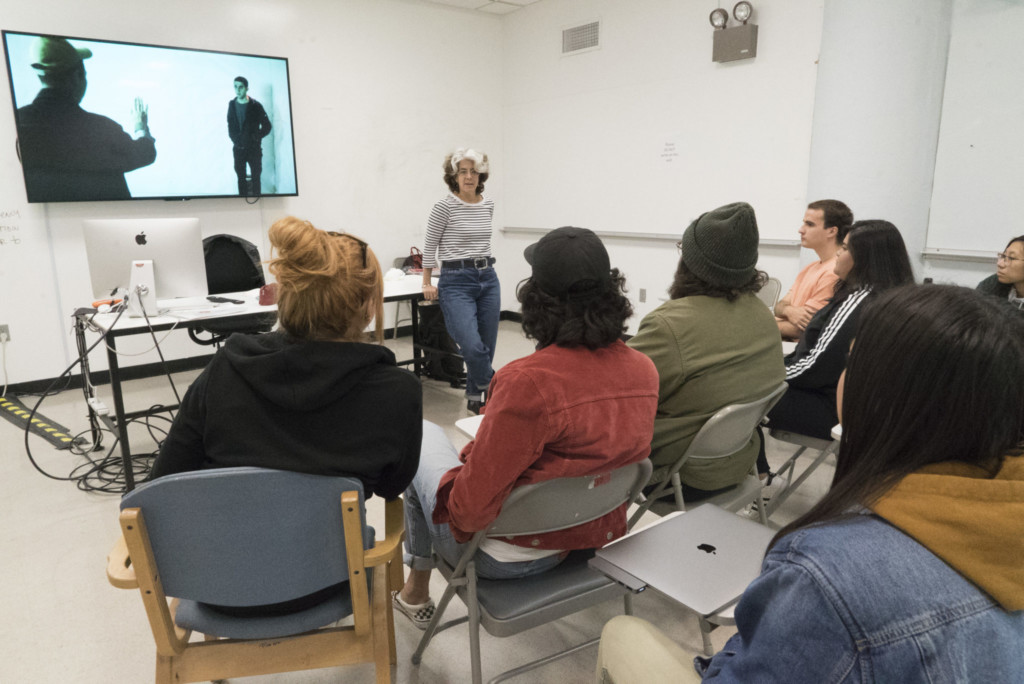 Instructor standing before a TV screen in a documentary class