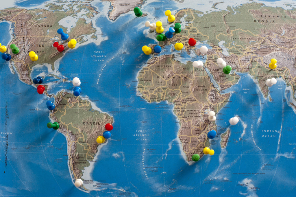 Multi-Colored Thumb Tacks Inserted in World Map