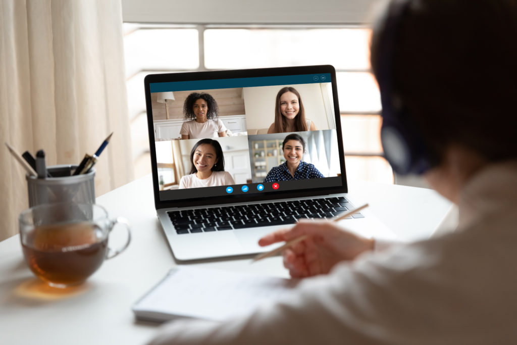 Man sits in front of computer looking at four other people in a web conference