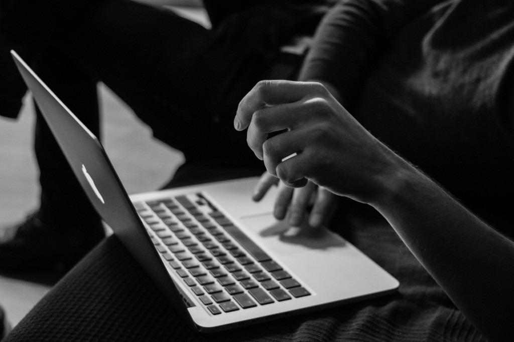 Black and white image of someone typing on a laptop