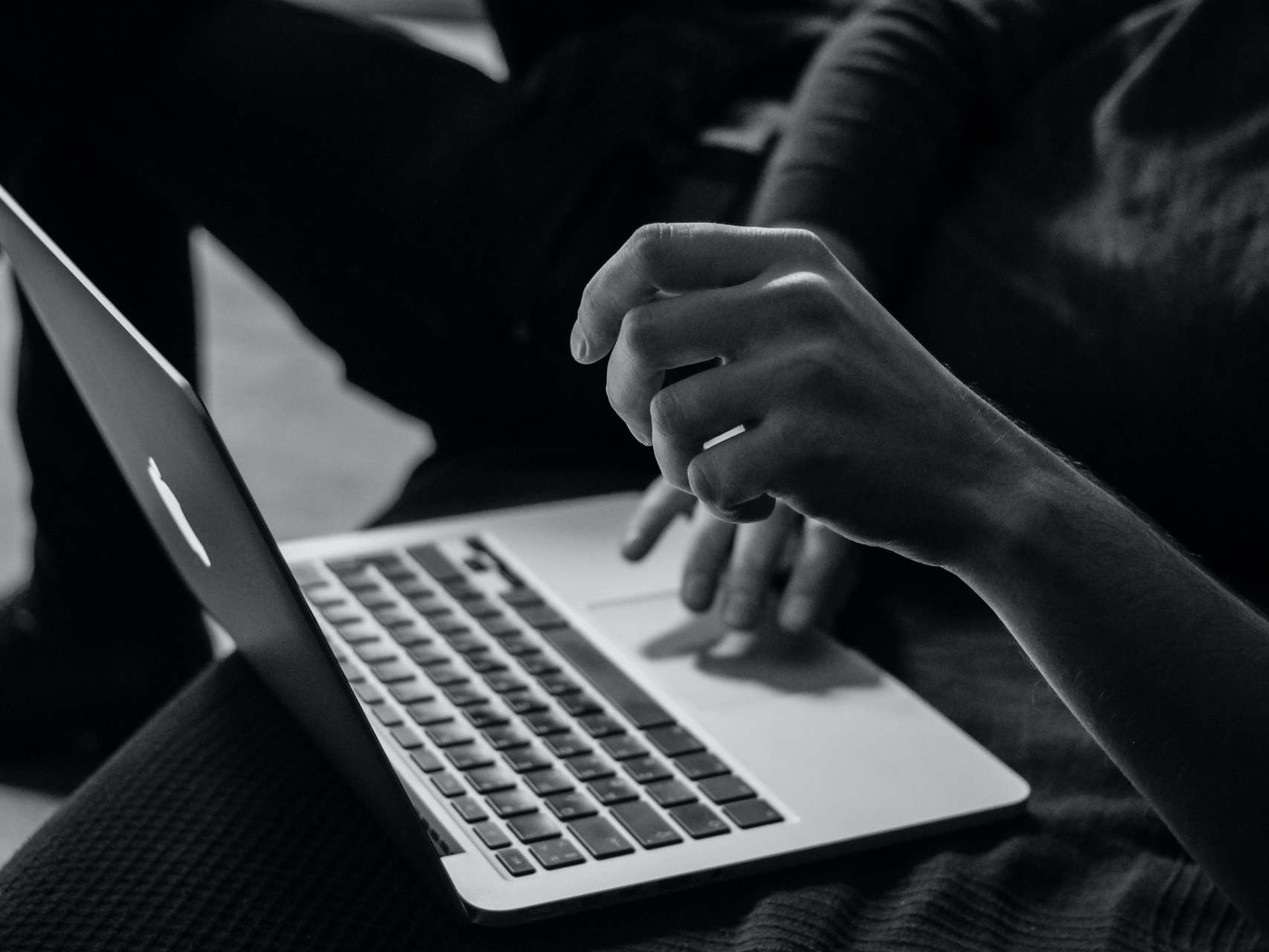 Black and white image of someone typing on a laptop