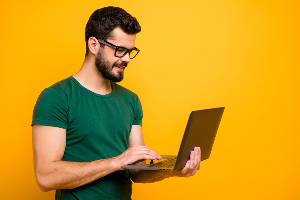 Man standing while working on his laptop