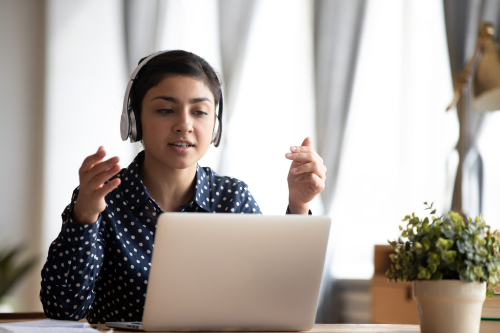 Woman wearing headphones talking to someone on her computer