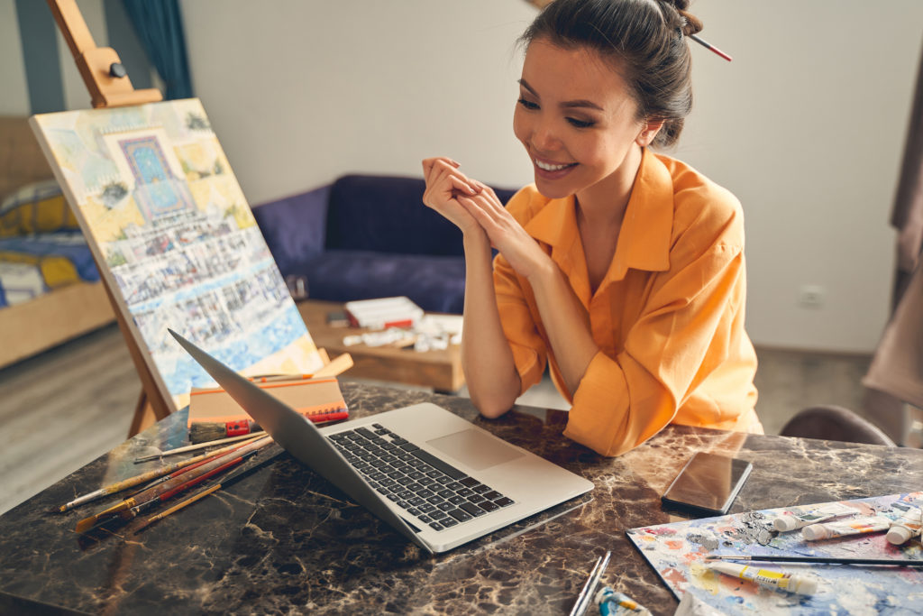 Women sitting in art room on a conference call on her laptop