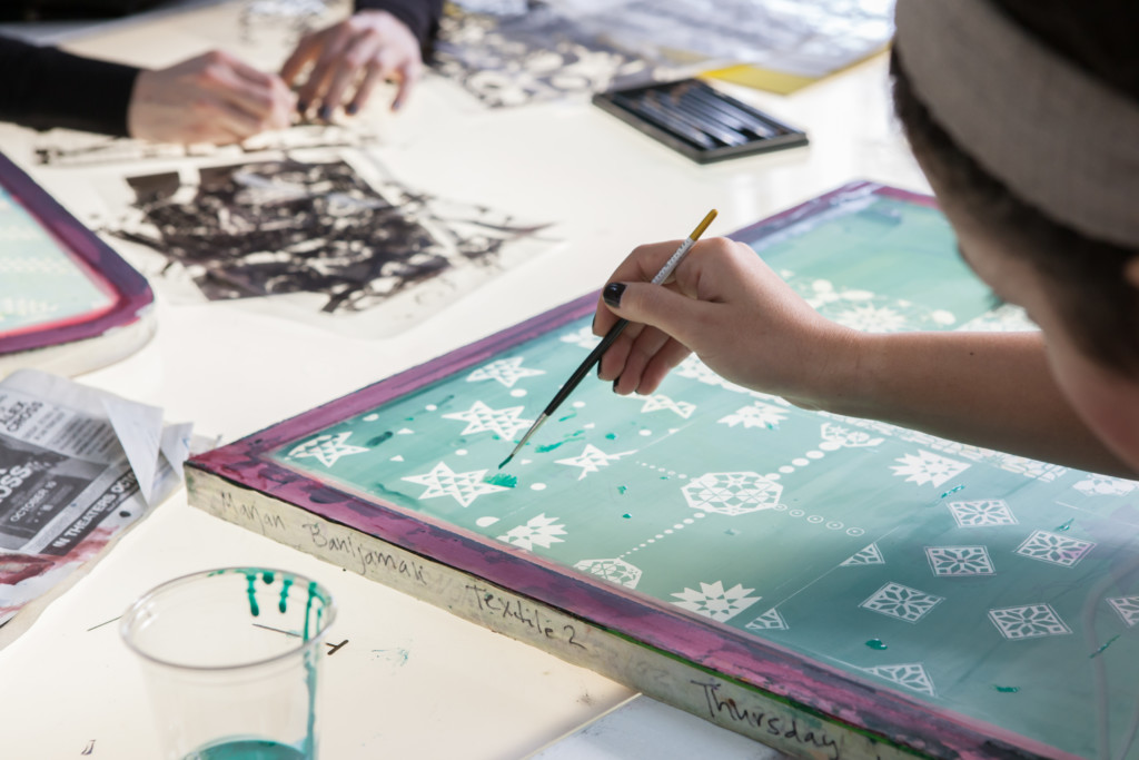 Woman applying watercolor paint to a collage